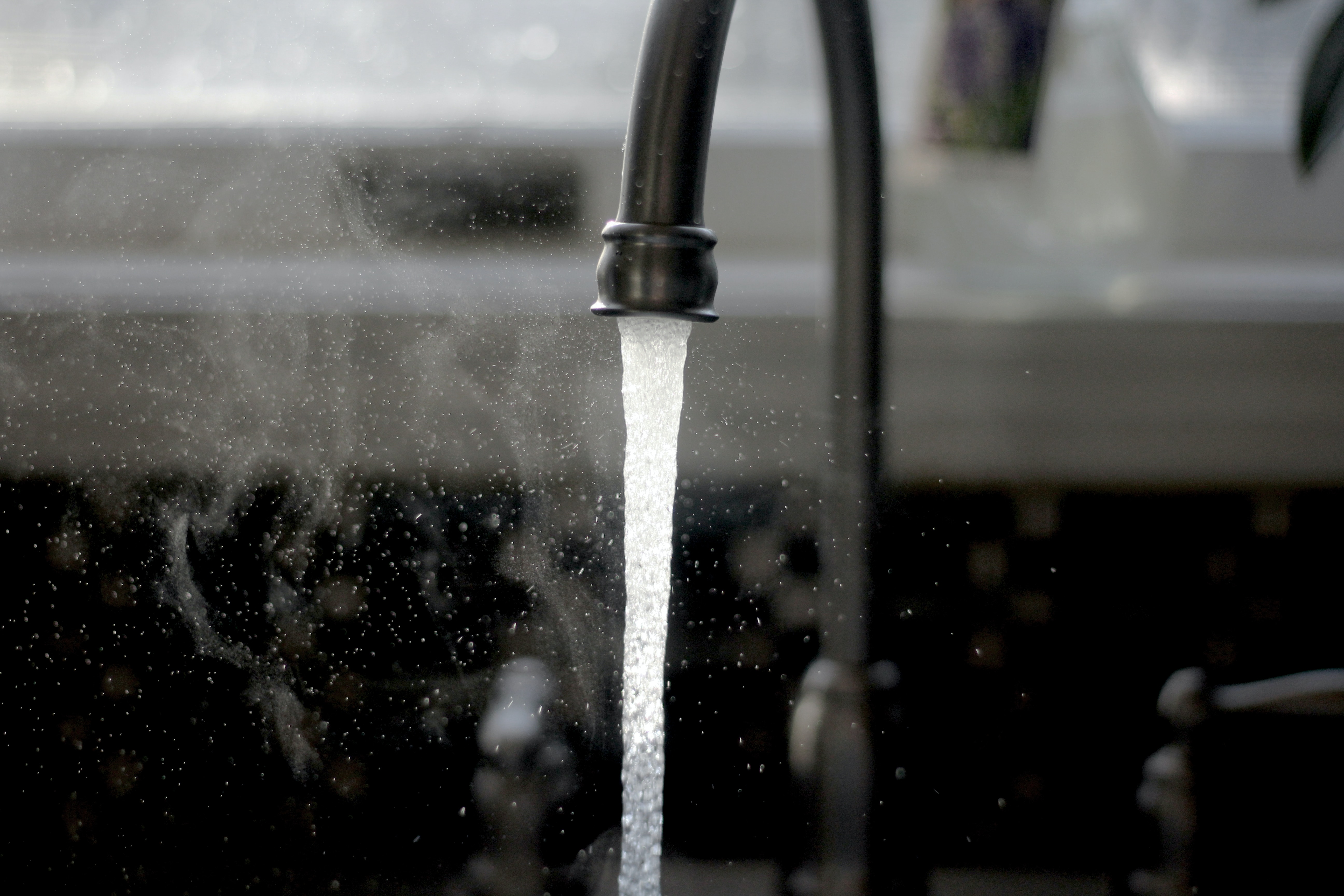 a black kitchen faucet that is releasing water
